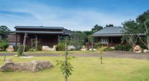The Frog Khao Yai Resort في Ban Tha Chang: منزل مع ساحة خضراء مع مبنى