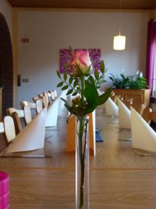 a vase with a rose in it sitting on a table at Landgasthof & Hotel "Merje" in Kreuztal