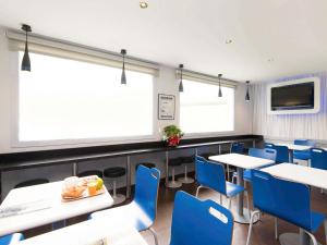 een eetkamer met tafels en blauwe stoelen bij Ibis Budget Bilbao Arrigorriaga in Arrigorriaga