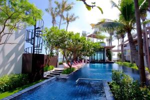 a swimming pool in a resort with palm trees at Eco Moment Beach Resort in Ban Laem Phak Bia (1)