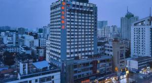 Vienna Hotel Nanning Train Station في نانينغ: مبنى شاهق به أضواء برتقالية في المدينة