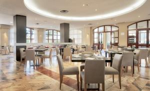 Un restaurante con mesas y sillas en una habitación. en Ilunion Golf Badajoz, en Badajoz