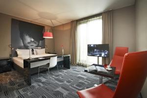 a bedroom with a bed and a desk and a television at LÉGÈRE HOTEL Tuttlingen in Tuttlingen