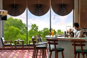 a man standing at a bar in a restaurant with chairs at Phoenix Resort Bac Ninh in Ðáp Cầu