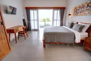 a bedroom with a bed and a desk and a window at Casa Serena Cemagi in Canggu