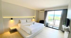 a bedroom with a white bed and a large window at Le Park Hotel in Thung Song