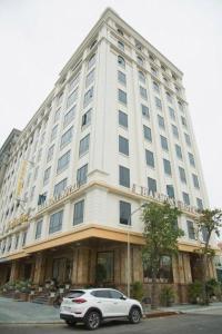 a white car parked in front of a large building at Bacninh Charming Hotel in Bồ Sơn