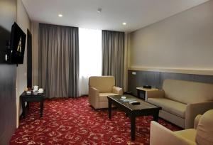 a hotel room with a couch and chairs and a table at pyramid suites Hotel in Banjarmasin