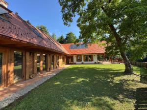 an exterior view of a house with a tree at Frida Farm Vendégház in Kétvölgy