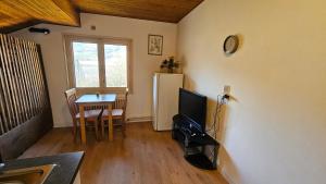 ein Wohnzimmer mit einem kleinen Tisch und einem Kühlschrank in der Unterkunft Mini cozy au MontBlanc in Sallanches