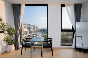 a dining room with a table and chairs and large windows at hiii Aura Pool Villa Hotel Pattaya Central in Pattaya Central