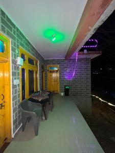 una stanza con tavolo, sedie e luci verdi di Royal Mount a Kasol