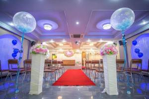 a banquet hall with blue and white columns and a red carpet at Manee Sangkha Hotel in Sangkha