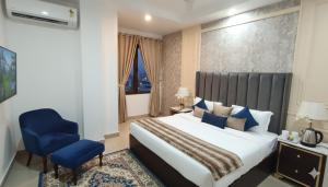 Un dormitorio con una cama grande y una silla azul. en Hotel Lime Pride Park Near By IGI Airport Delhi, en Nueva Delhi
