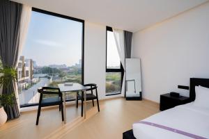 a bedroom with a table and chairs and large windows at hiii Aura Pool Villa Hotel Pattaya Central in Pattaya Central +187 photos