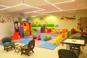 uma sala de jogos infantil com uma área de recreação com mesas e cadeiras em DNC Shevaroys Resorts & Spa em Yercaud
