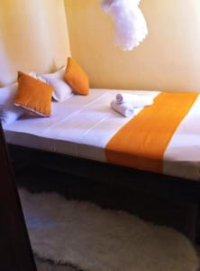 - un lit avec des draps et des oreillers orange et blancs dans l'établissement House of Hera, à Kisumu