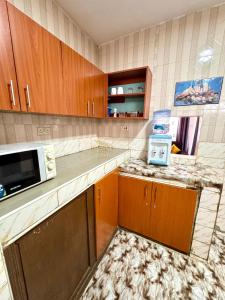 une cuisine avec des armoires en bois et un micro-ondes dans l'établissement House of Hera, à Kisumu