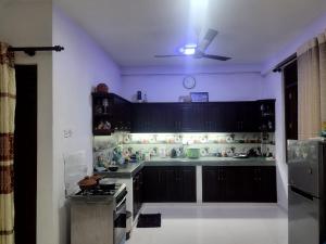 een keuken met zwarte kasten en een fornuis bij Prince House in Piliyandala