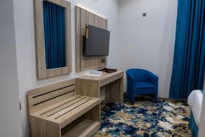 a room with a desk with a tv and a blue chair at فندق برادايس لاند الشهداء Paradise Land Hotel Al-Shohada in Al ‘Utaybīyah