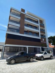zwei Autos vor einem Gebäude geparkt in der Unterkunft Apartamento Vó Lêla in Bombinhas
