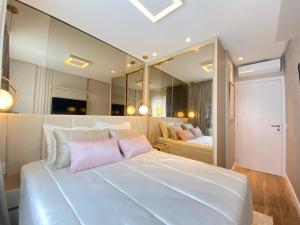 ein großes weißes Bett mit rosa Kissen in einem Zimmer in der Unterkunft Apartamento Vó Lêla in Bombinhas