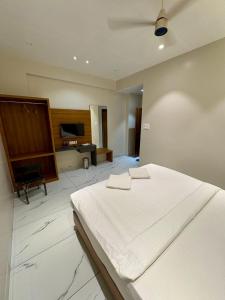 een slaapkamer met een wit bed en een piano bij HariPriya Executive in Tuljapur +3 foto's