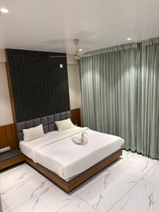 een slaapkamer met een groot bed met witte lakens bij HariPriya Executive in Tuljapur