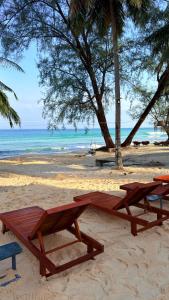 duas mesas de piquenique em uma praia perto do oceano em Umi Resort 菩提有米 em Sihanoukville