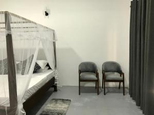a bedroom with a bed and two chairs at Amelia Villa in Gandara West