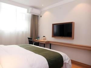 ein Hotelzimmer mit einem Bett und einem Fernseher an der Wand in der Unterkunft GreenTree Inn Express Cangzhou Yunhe District Mingzhu Market in Cangzhou