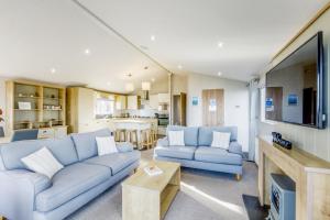 a living room with two blue couches and a kitchen at Lodge 72 at Riviera Bay Coastal Retreat in Brixham
