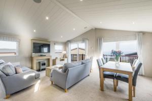 Una sala de estar con un sofá, una mesa y sillas. en Lodge 66 at Riviera Bay Coastal Retreat, en Brixham