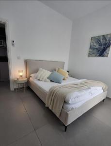 a bed in a white room with a lamp on a table at סוויטת בארי , שלווה בגליל העליון in Mishmār Hāyardin