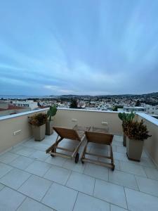 a balcony with a table and chairs on a roof at ISLAND Time Deluxe Apartment Downtown 3 floors in Chios
