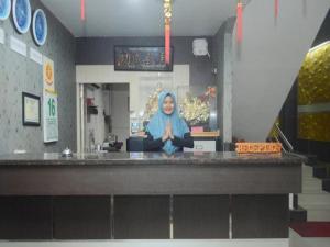 una mujer parada detrás de un mostrador en un restaurante en Majestiq Hotel by TripleTree, en Pekanbaru
