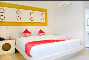 Un dormitorio con una gran cama blanca con almohadas rojas. en Majestiq Hotel by TripleTree, en Pekanbaru