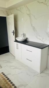 The Breeze Escape Harare في هراري: حمام أبيض مع حوض ومكتب