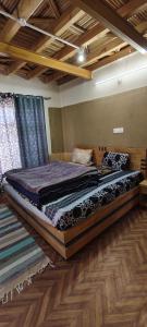 un letto grande in una stanza con pavimento in legno di Wangmo homes, Spiti a Kaja