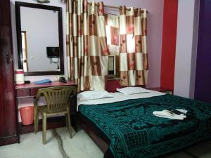 a bedroom with a bed and a desk and a mirror at Hotel Mayur in Gwalior