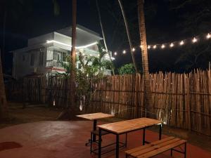 Dos mesas de picnic frente a una valla por la noche. en Nature's Inn Luxury Villa Morjim Goa, 4bhk and Sparkling Pool, en Morjim