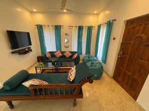 Una sala de estar con un sofá y un televisor. en Nature's Inn Luxury Villa Morjim Goa, 4bhk and Sparkling Pool, en Morjim