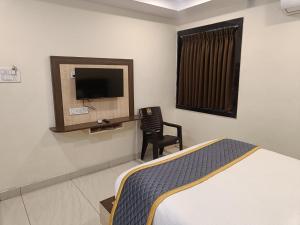 a bedroom with a bed and a chair and a tv at DVR GRAND-AC Rooms in Visakhapatnam