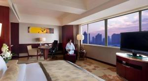 WYNDHAM HOTEL XIAN في شيان: امرأة جالسة في غرفة مع نافذة كبيرة