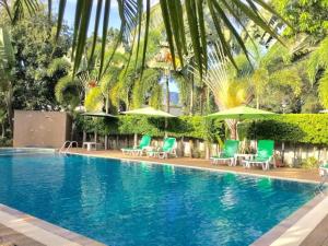 a swimming pool with green chairs and umbrellas at Wild Orchid Villa Krabi in Ao Nam Mao