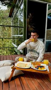 ANCESTRAL GLAMPING في باربوسا: رجل يجلس على طاولة شرب كوب من القهوة