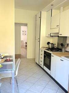 uma cozinha com armários brancos, uma mesa e uma sala de jantar em Appartamento DIMORA GUIDI 3 camere 2 bagni URBINO em Urbino