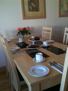 een houten tafel met borden en keukengerei erop bij Albany Lodge in Portrush