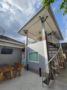 een patio met een houten bank en een trap bij een huis bij Sun Poolvilla Bangsaray in Bang Sare