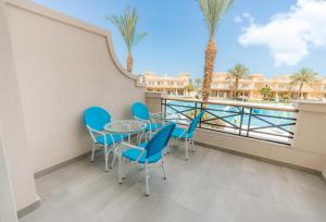 a balcony with a table and chairs and palm trees at Flow Spectrum Resort Sahl Hasheesh in Hurghada